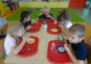 Dzieci siedzą przy stoliku i smakują drożdży.